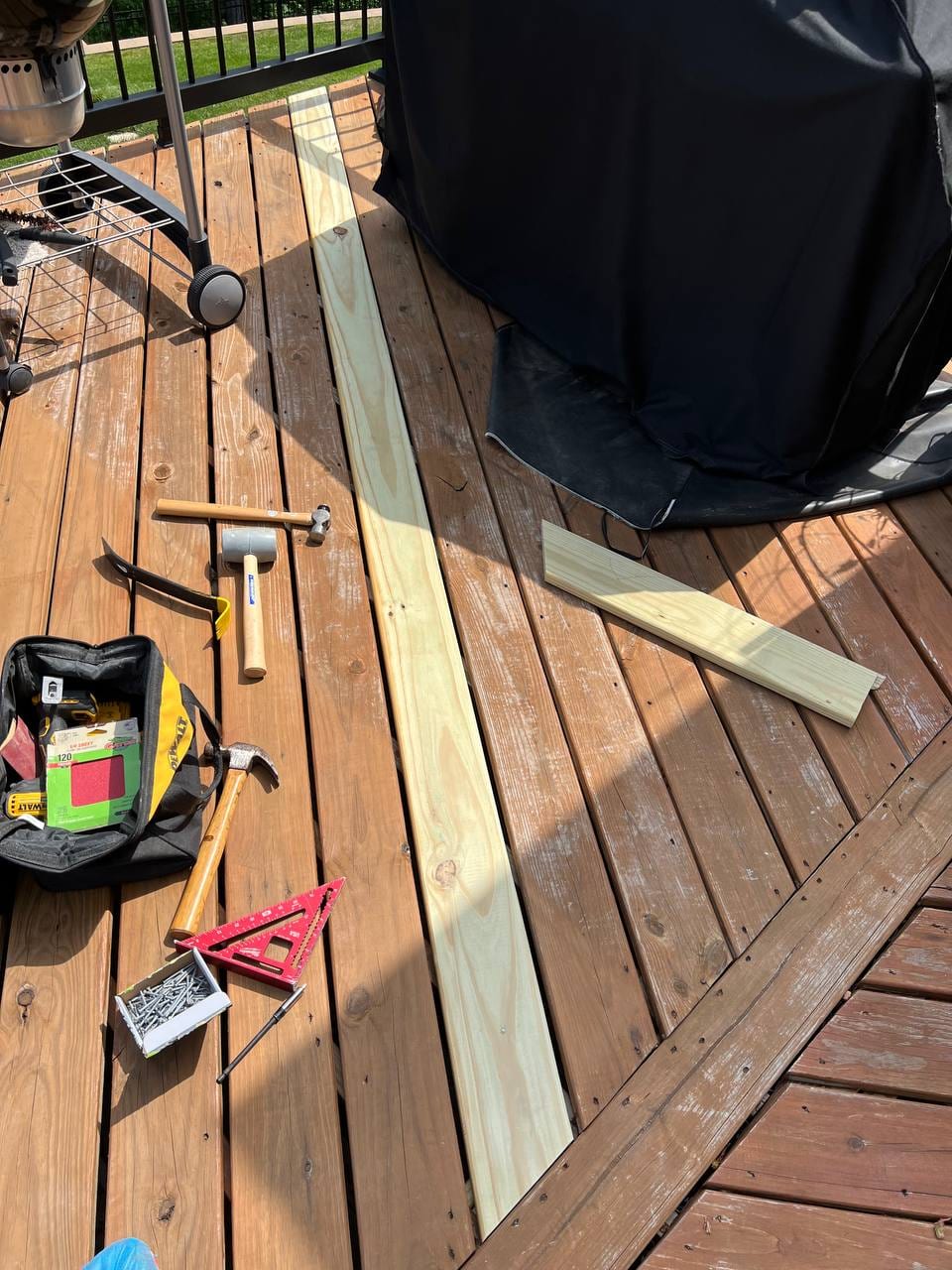 Deck with replacement lumber and tools laid out for board repair