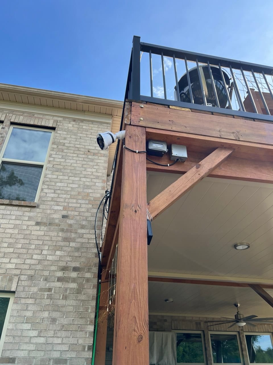 Outdoor security camera mounted on a covered deck post, wired to a weatherproof junction box