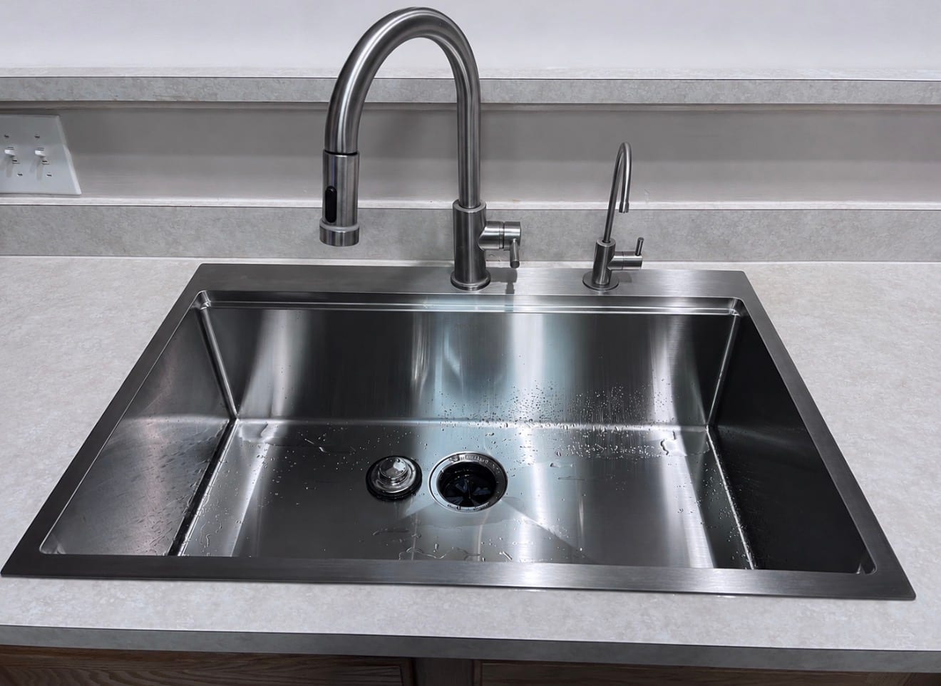 New stainless steel drop-in kitchen sink with pull-down faucet and filtered-water tap after replacement