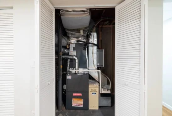 Tidy mechanical room — furnace and ductwork behind louvered doors